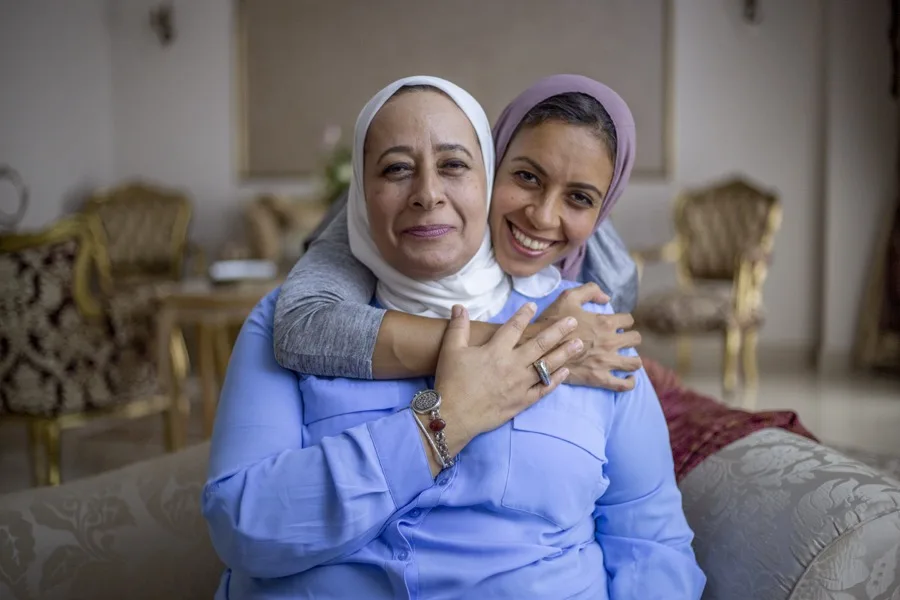 An adult daughter embracing her elderly mother